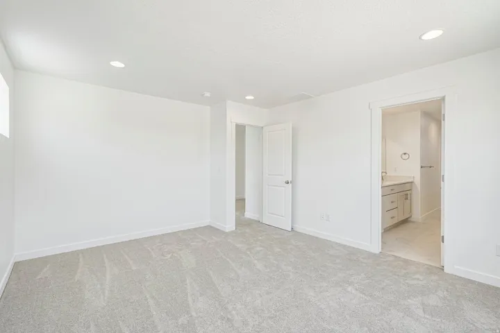Spacious room featuring light-toned carpeting, recessed ceiling lighting, and crisp white walls