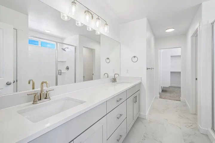 Dual vanity featuring light-toned cabinetry, brushed nickel fixtures, and a white countertop