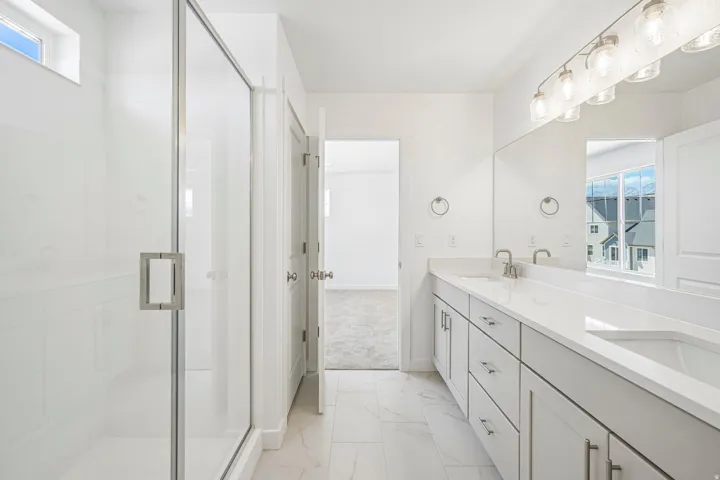 Spacious bathroom featuring a double vanity with stone countertops, undermount sinks, and brushed nickel fixtures