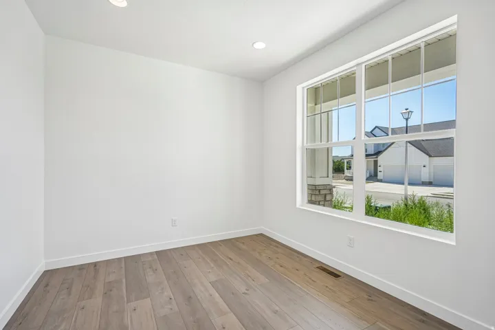 Bright room featuring wood-finish flooring, recessed lighting, white walls, and a large multi-pane window