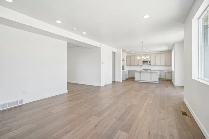 Open-concept living area featuring light wood-finish flooring, recessed lighting, and a neutral color palette