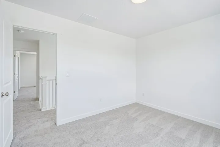 Bright room featuring neutral carpeting, white walls, white baseboards, and a flush-mount ceiling light fixture