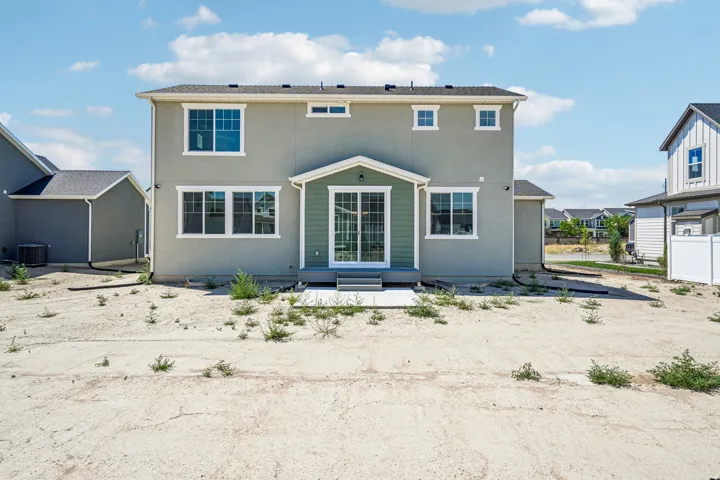 Rear exterior featuring a sliding glass door, a covered patio, multiple windows with white trim, and a light gray stucco finish
