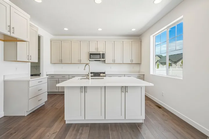 Modern kitchen featuring an expansive center island with an integrated sink and gooseneck faucet