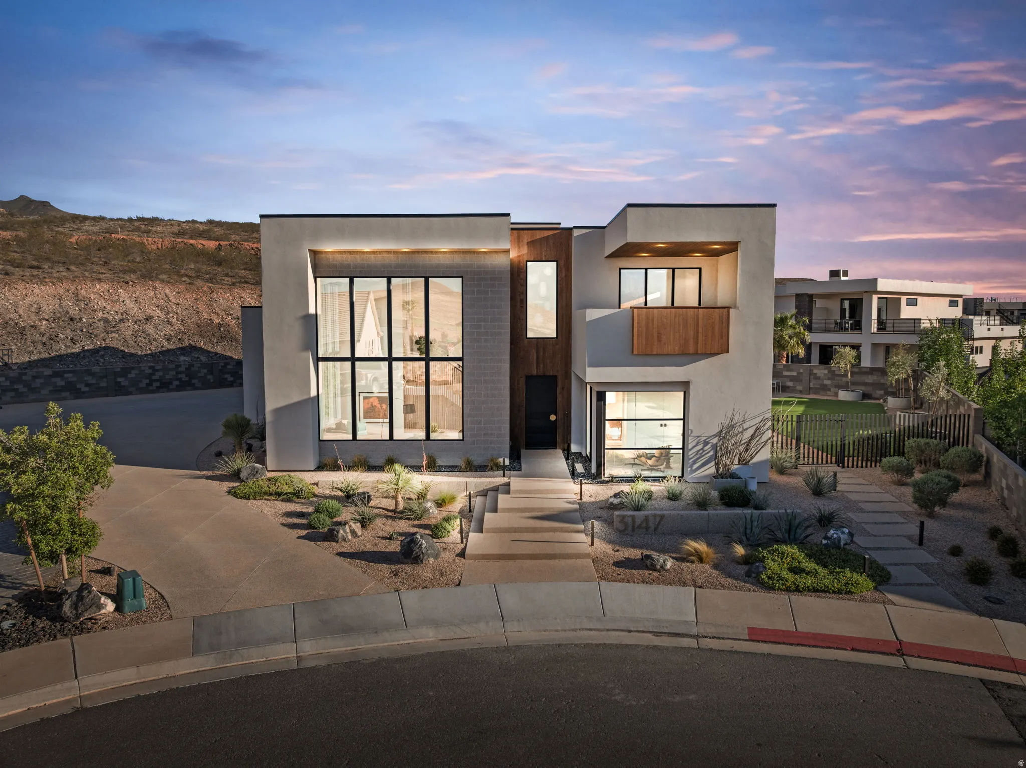 Modern home featuring a balcony, stucco siding, driveway, and a garage