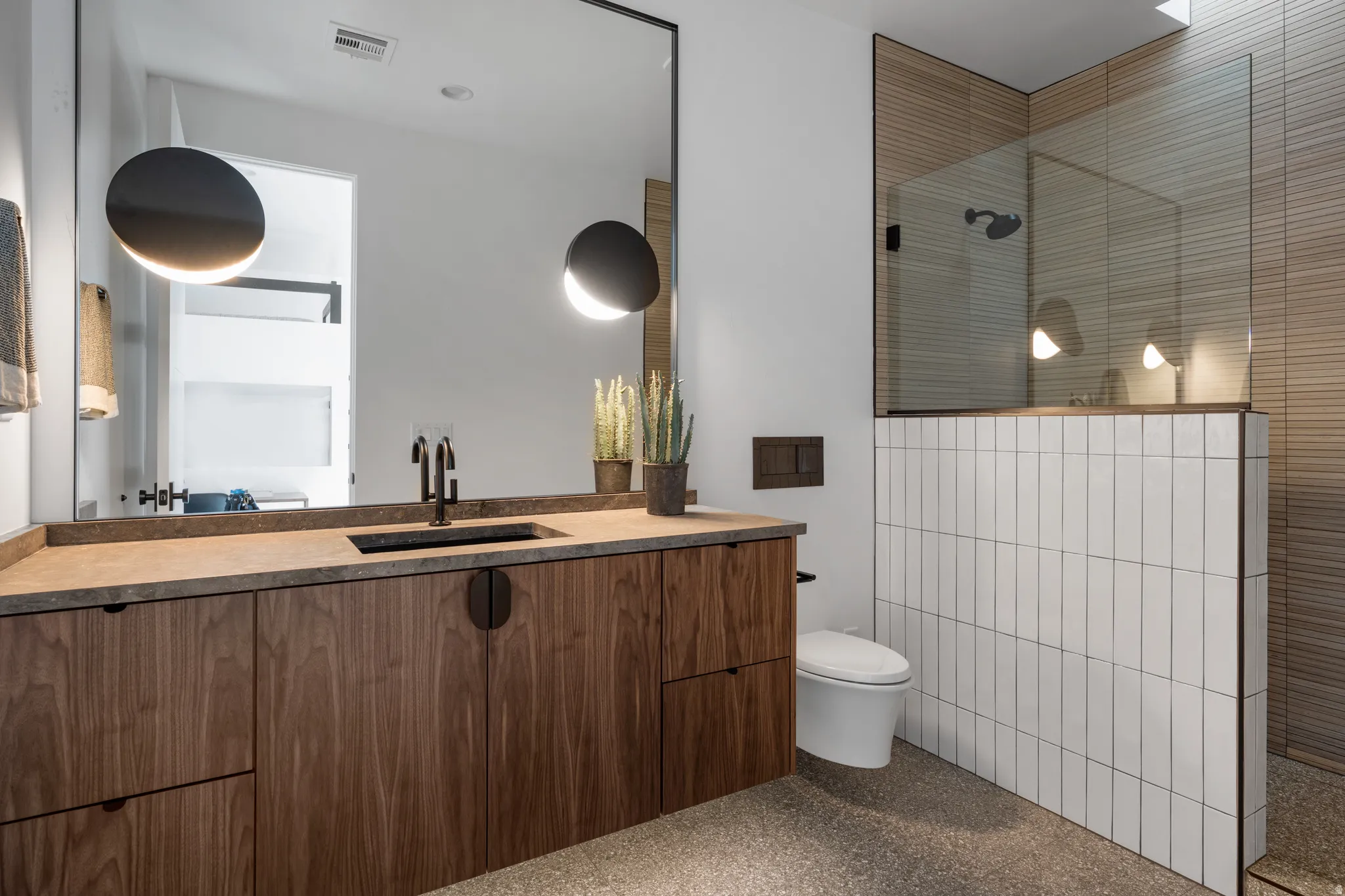 Bathroom featuring light aggregate flooring, vanity, and a walk in shower