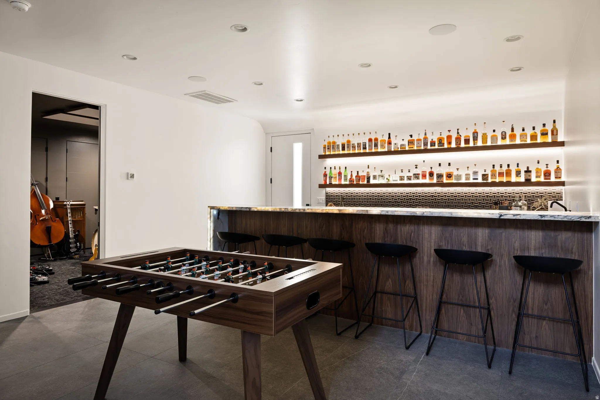 Recreation room with bar with sink, dark tile patterned flooring, and recessed lighting