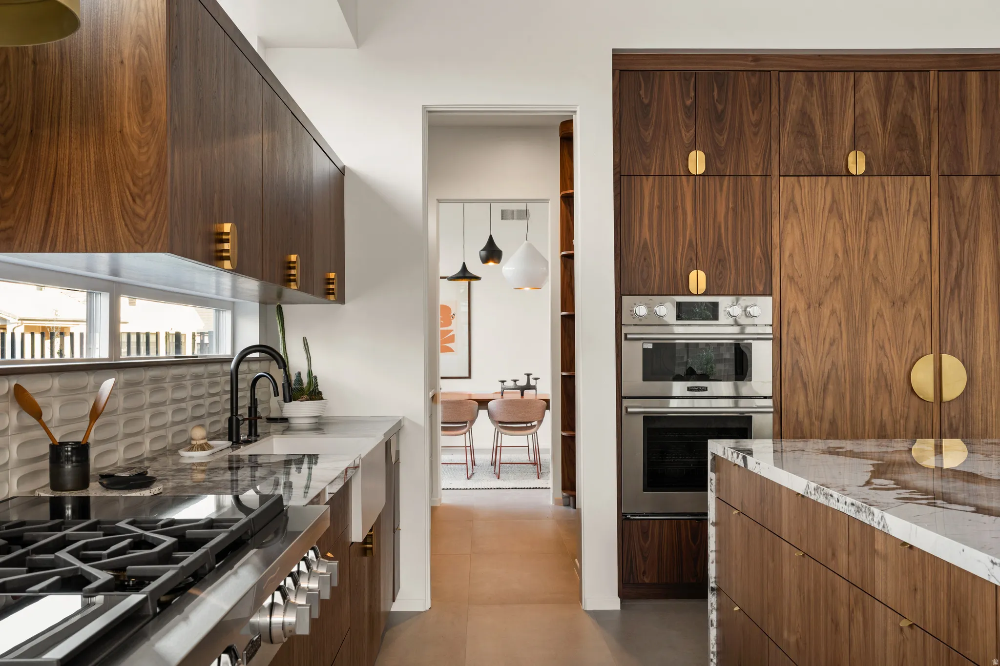 Kitchen with modern cabinets, light stone counters, stainless steel appliances, and dark wood finish cabinets