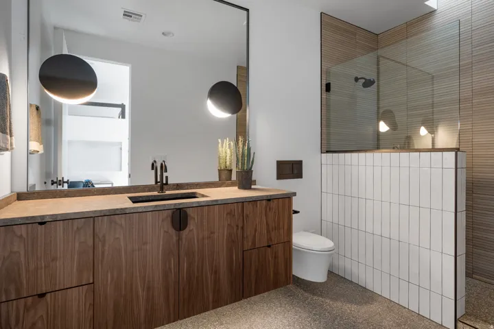 Bathroom featuring light aggregate flooring, vanity, and a walk in shower