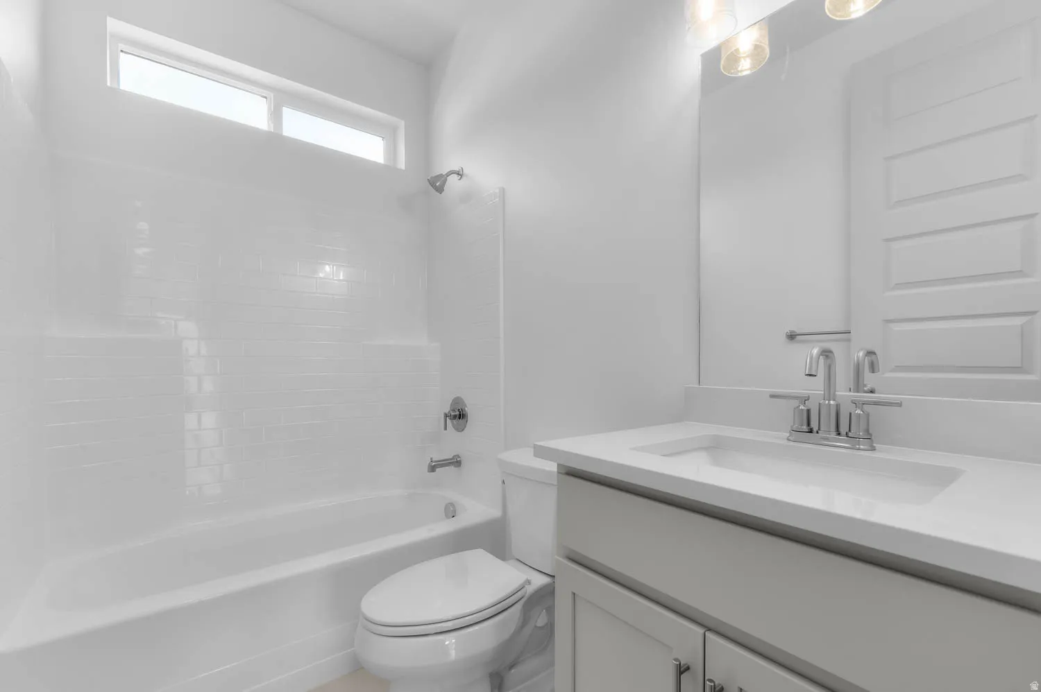 Bathroom featuring a tub/shower combination with subway tile surround, a built-in vanity with light-toned cabinetry, a polished chrome faucet, and a rectangular undermount sink