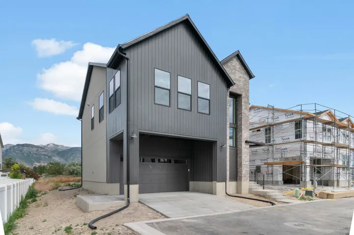 Contemporary multi-story residence featuring a dark gray vertical siding facade and a light gray brick accent tower