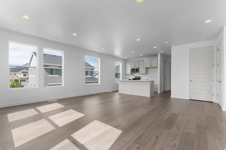 Open-concept living area featuring wood-finish flooring, recessed ceiling lighting, and multiple windows