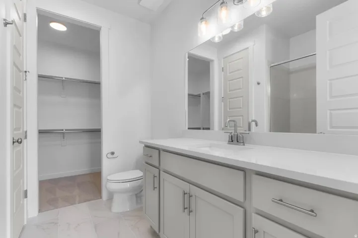 Spacious bathroom featuring a double vanity with light gray cabinetry, a white countertop, and contemporary hardware