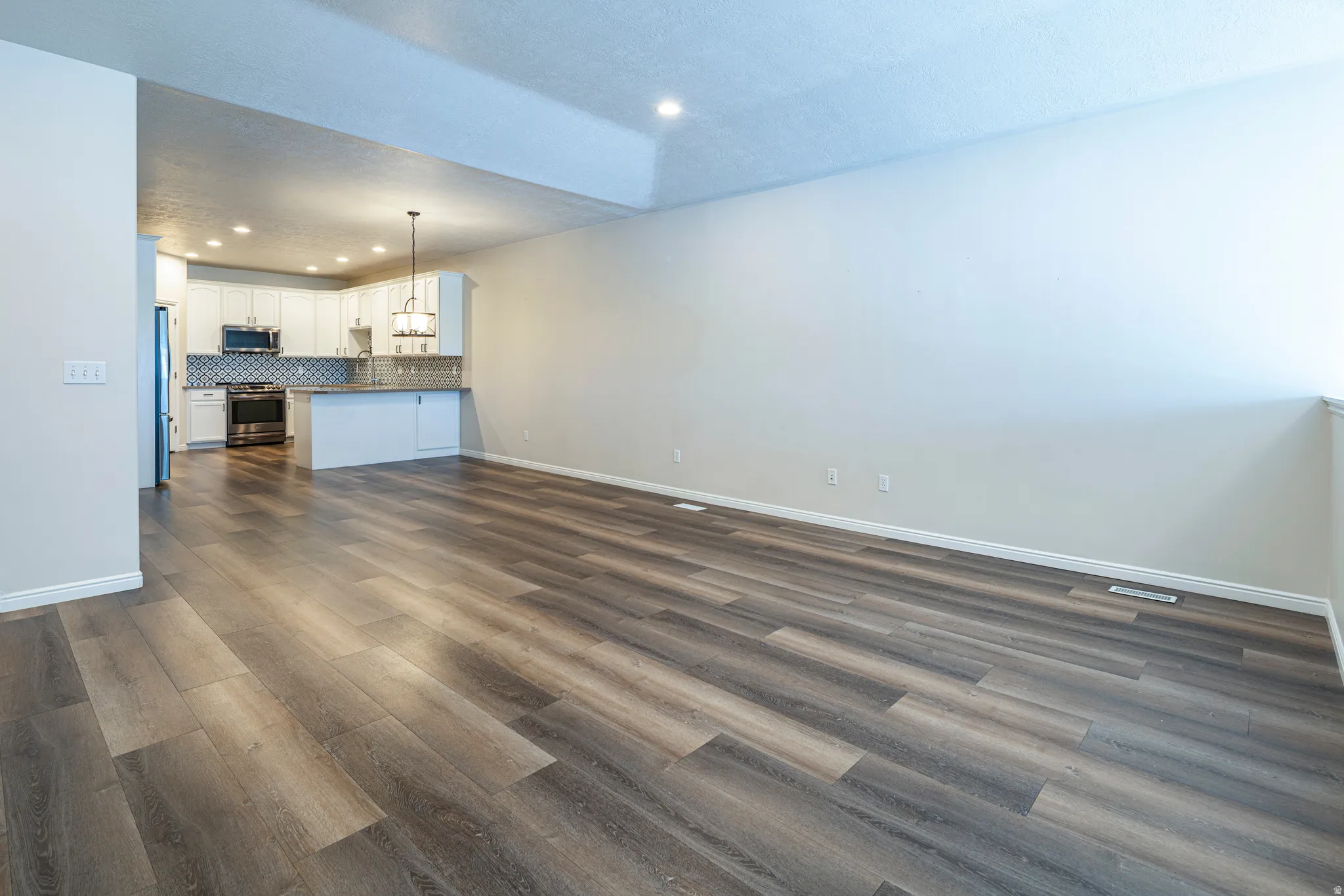 Unfurnished living room featuring recessed lighting and dark wood-style flooring
