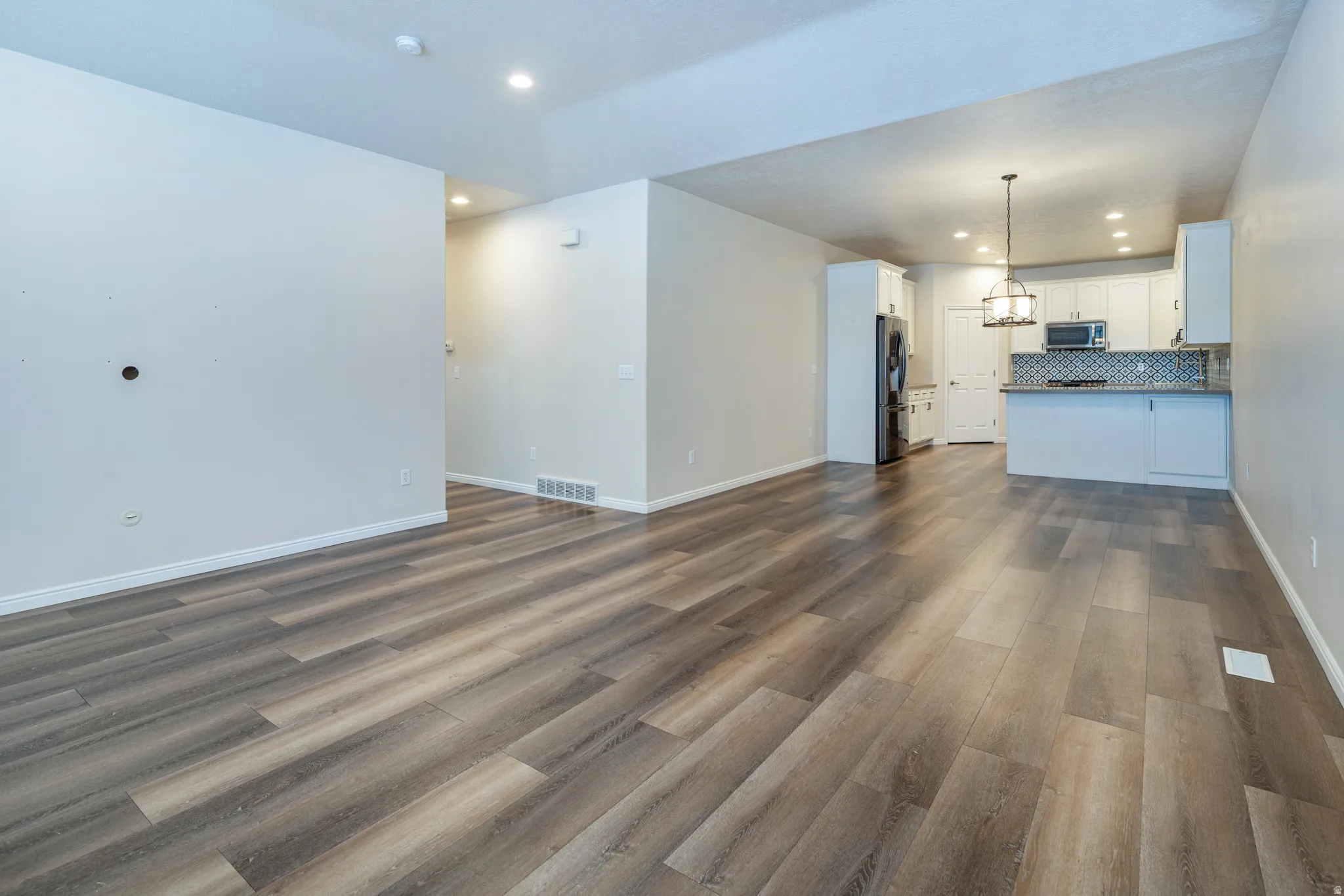 Unfurnished living room with recessed lighting and dark wood-style floors