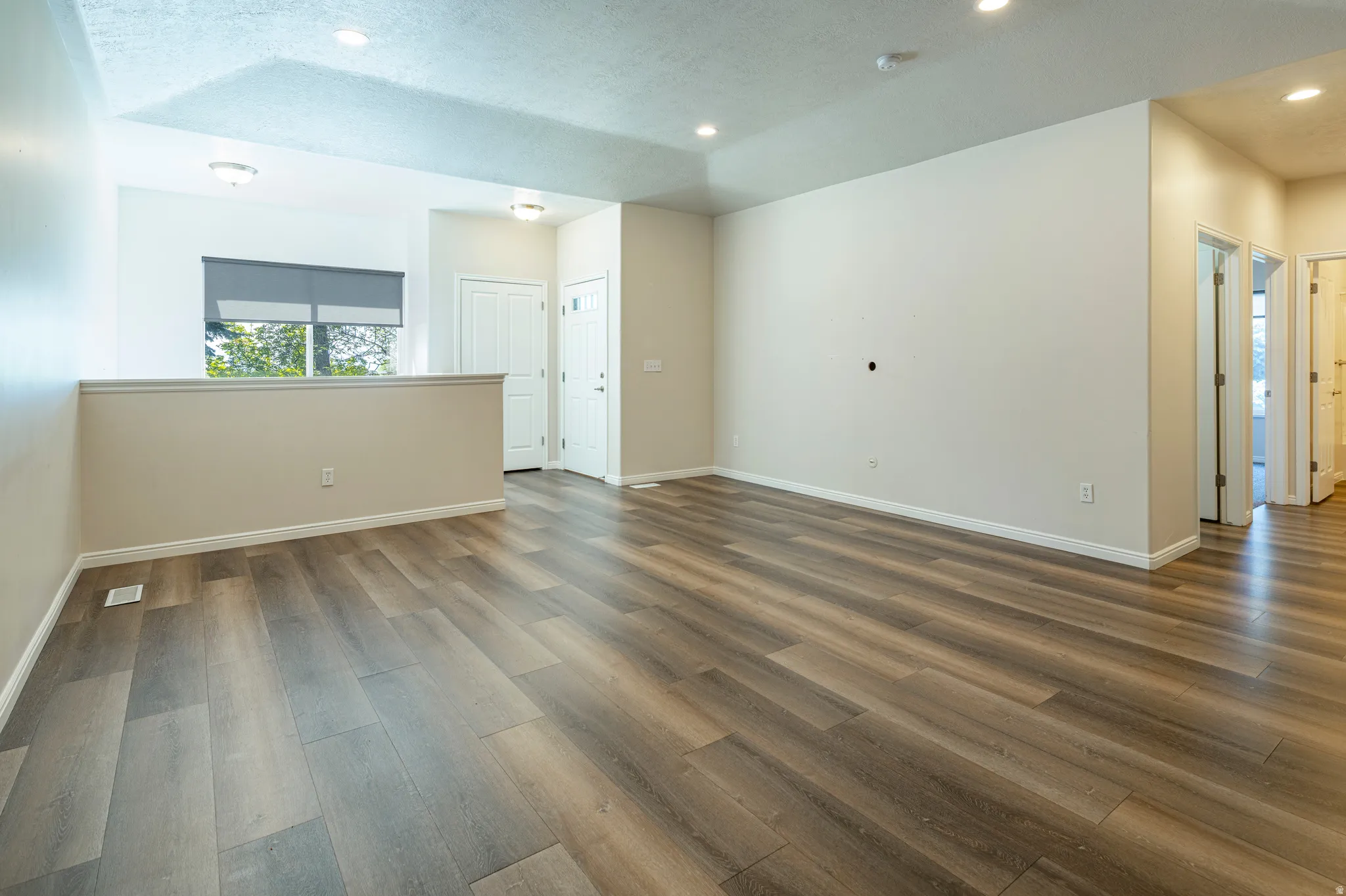 Empty room with dark wood-style flooring, recessed lighting, and a textured ceiling