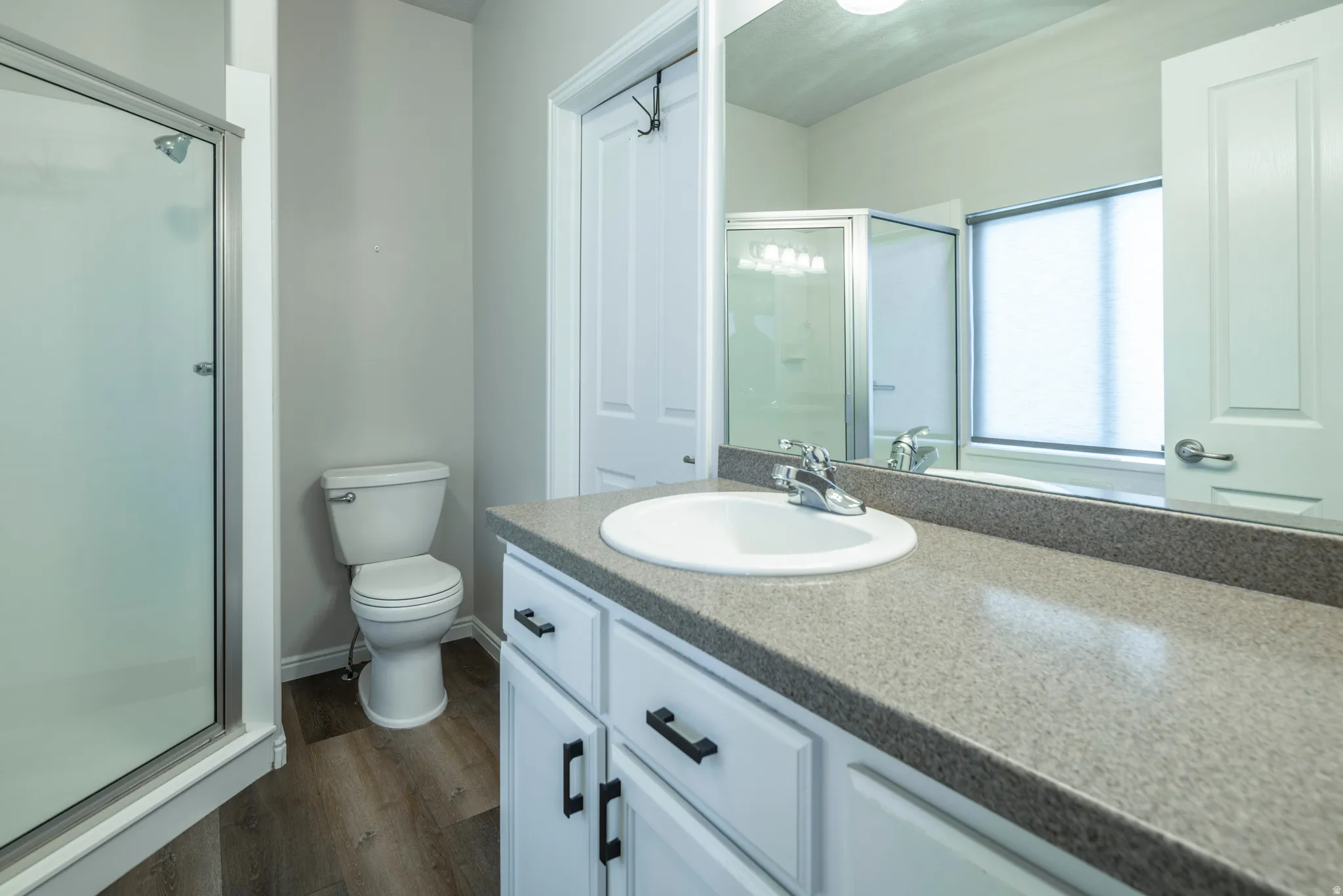 Full bathroom with a stall shower, vanity, and dark wood finished floors