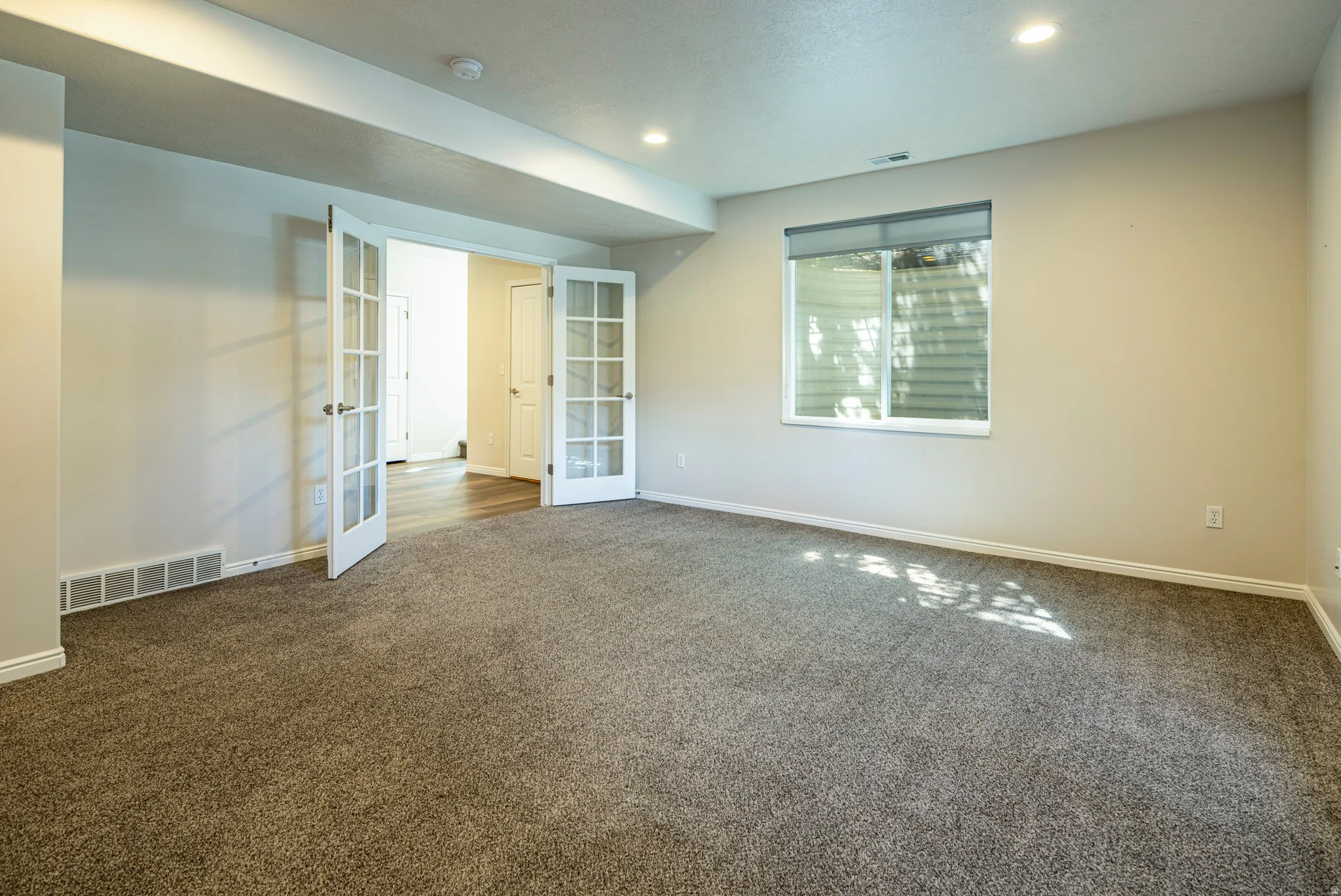 Spare room featuring french doors, dark colored carpet, and recessed lighting