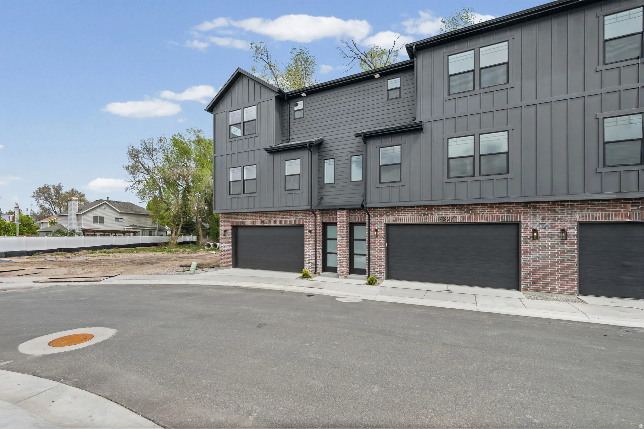 View of front of home with board and batten siding, a garage, and brick siding