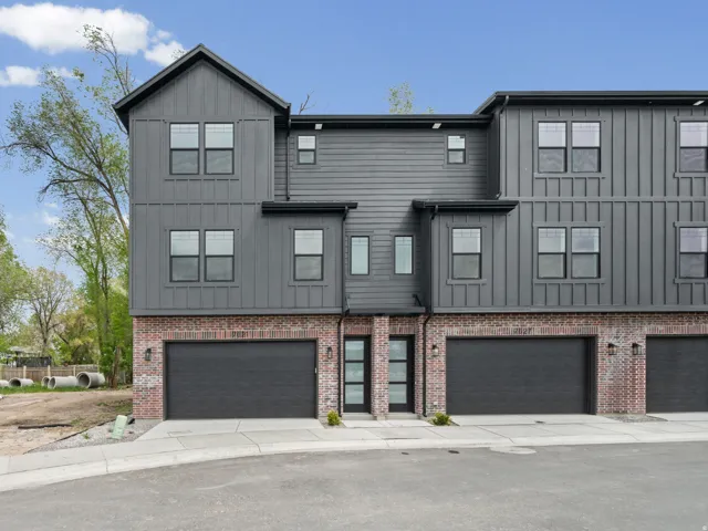 Modern inspired farmhouse with board and batten siding, an attached garage, driveway, and brick siding