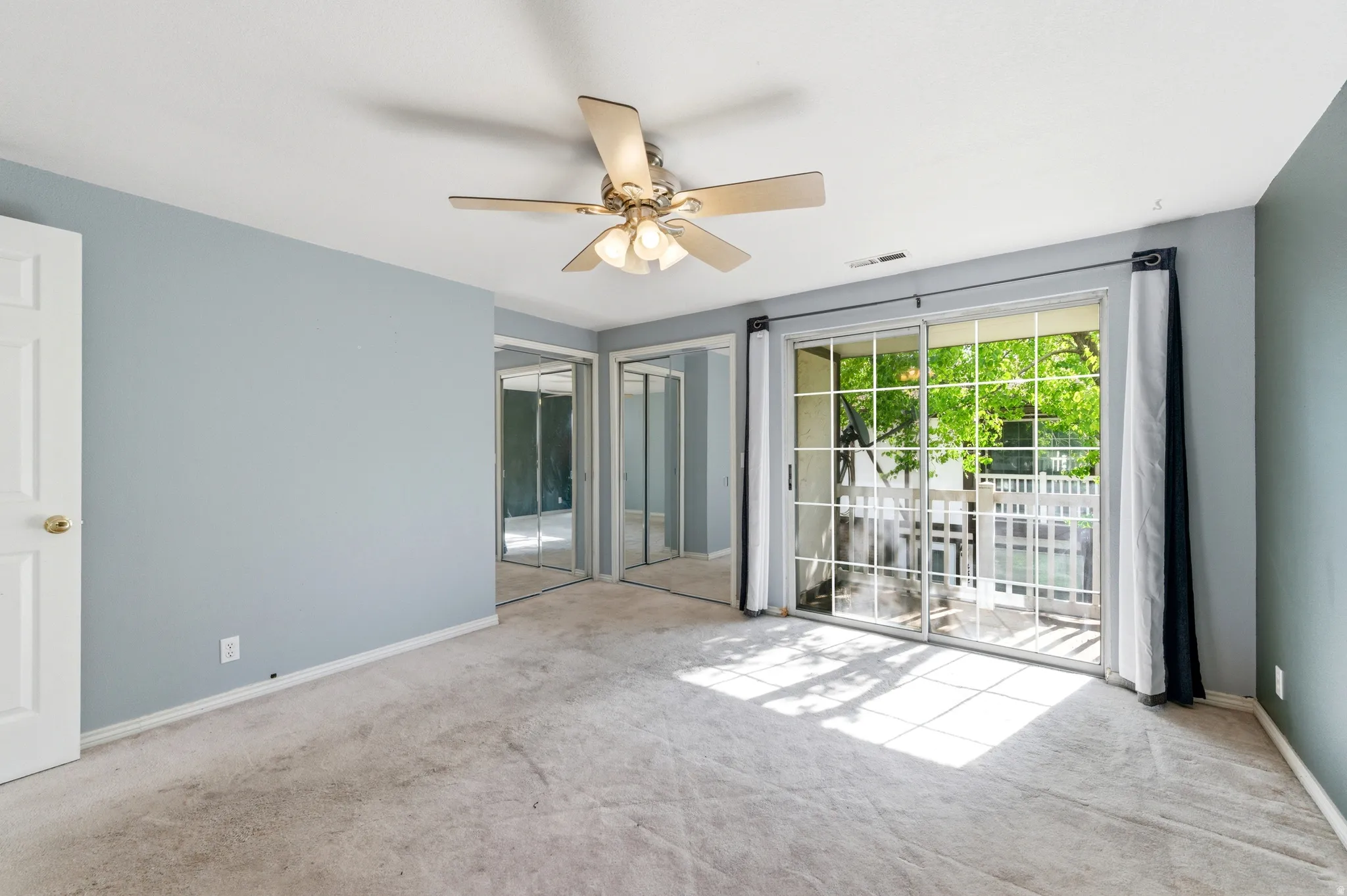 Bedroom featuring Balcony, carpet, ceiling fan, and multiple closets