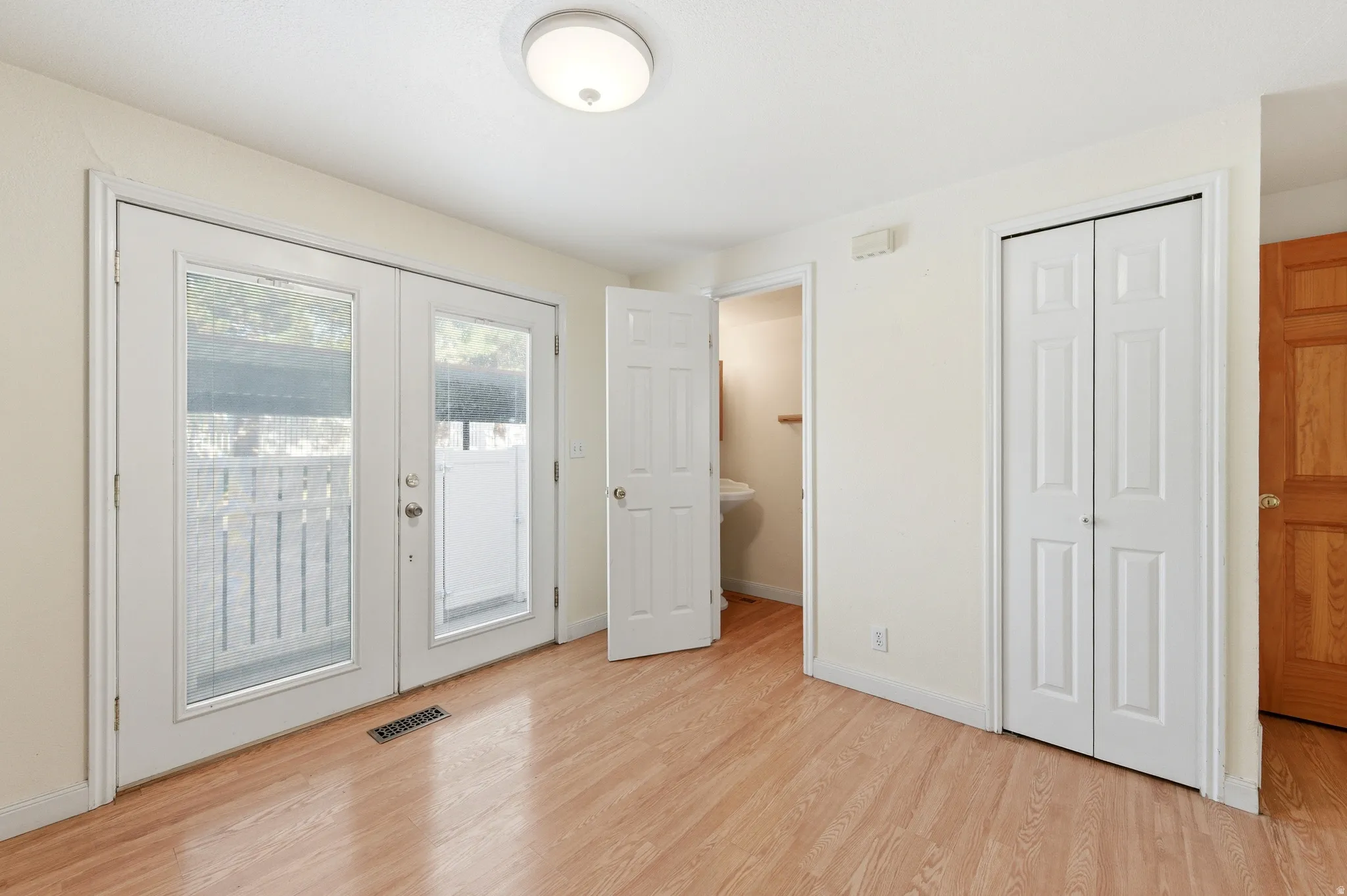 Kitchen with access to outside, light wood-style flooring, french doors, and a half bathroom.