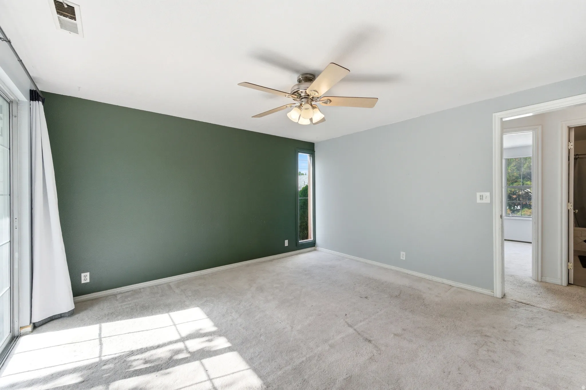 Bedroom featuring light colored carpet, a ceiling fan, and plenty of natural light