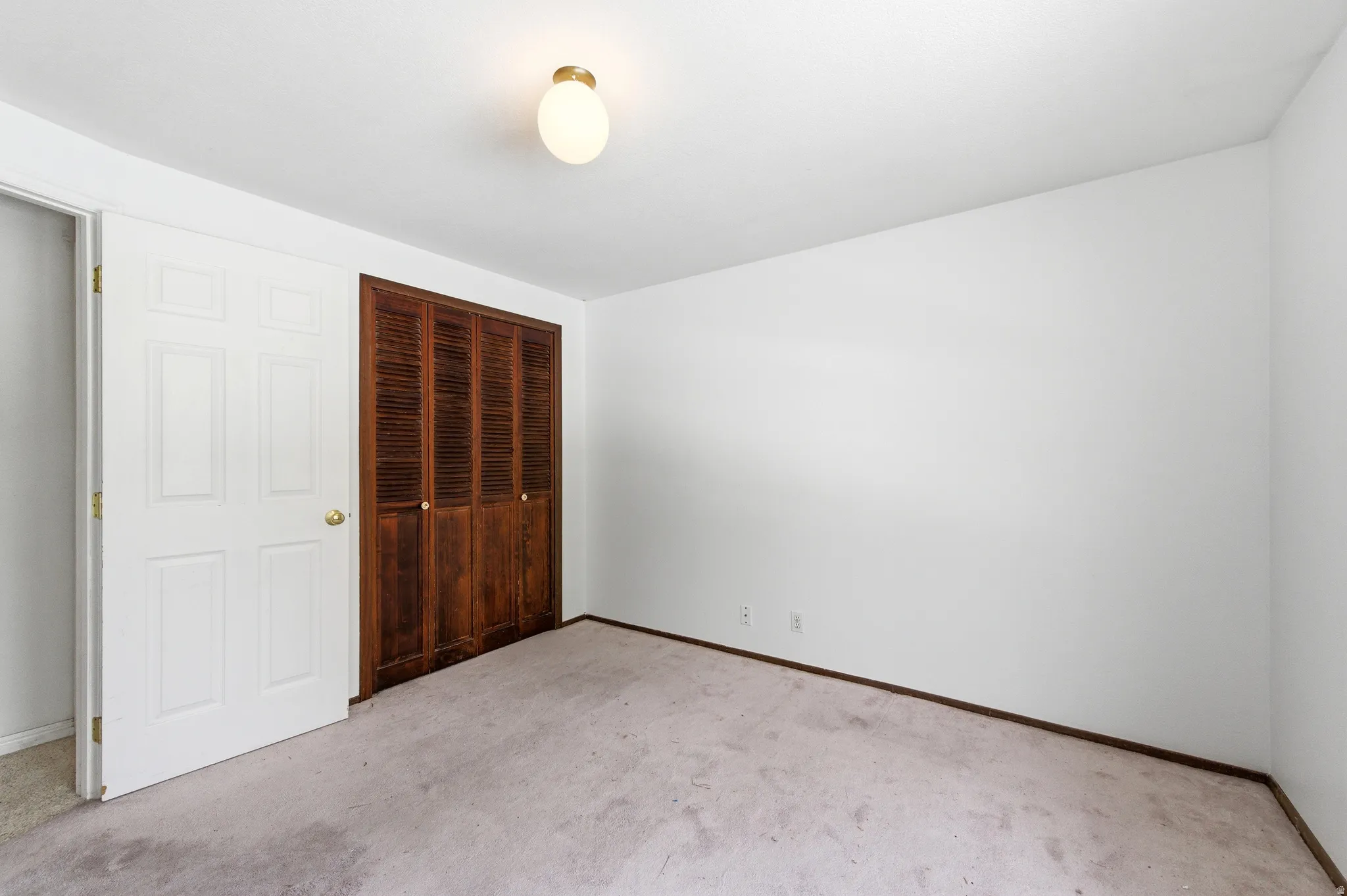Bedroom with light colored carpet and a closet