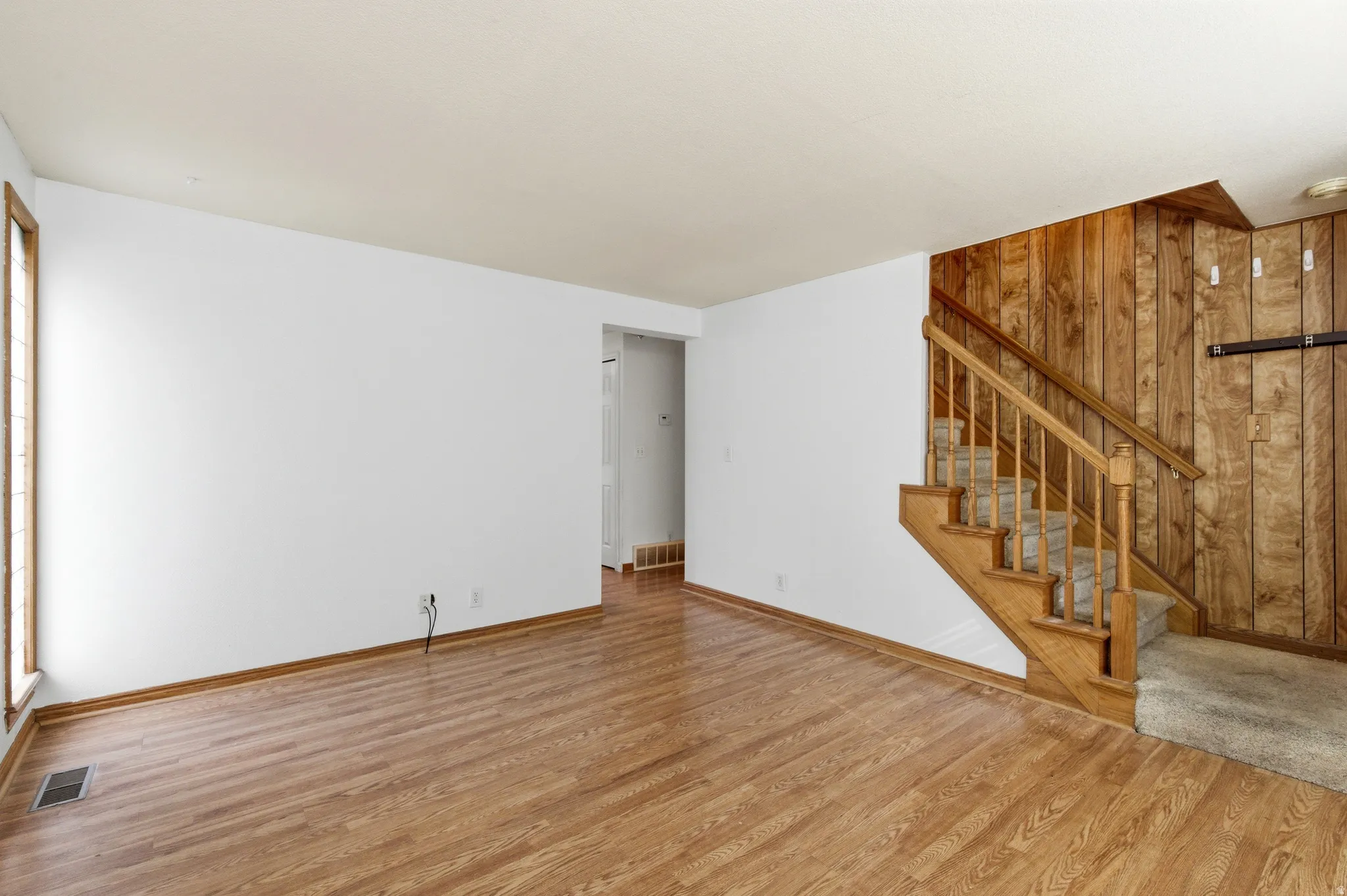 Unfurnished living room featuring wooden walls and wood finished floors