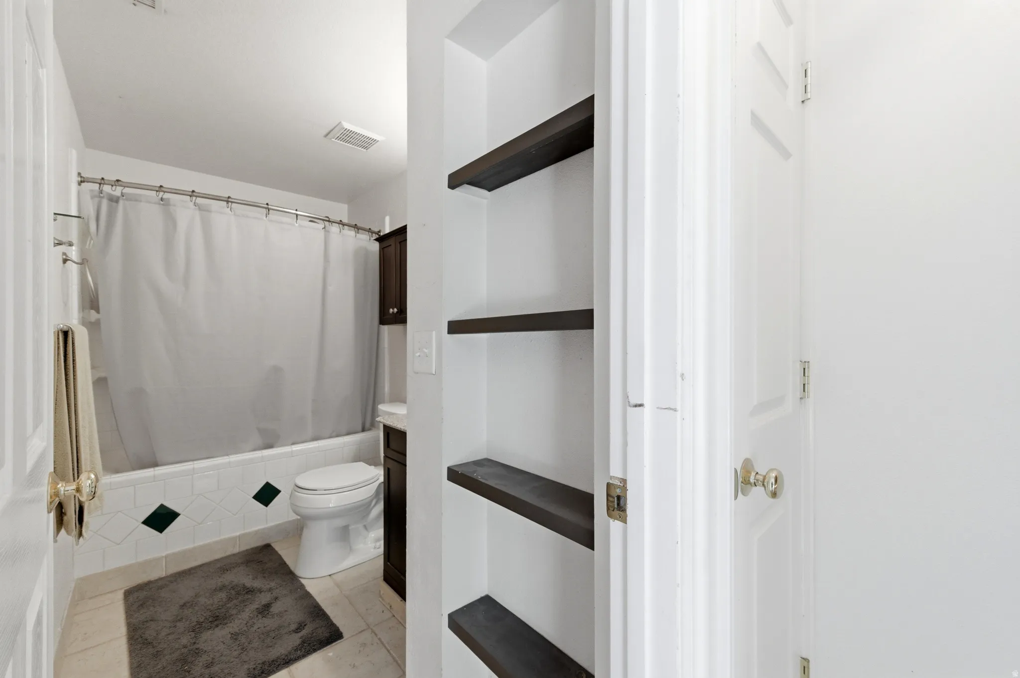 Full bathroom featuring shower / bathtub combination with curtain, light tile patterned floors, and vanity