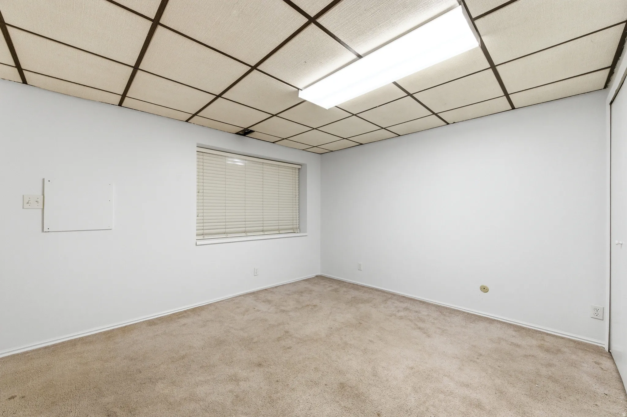 Living room with light colored carpet and a paneled ceiling