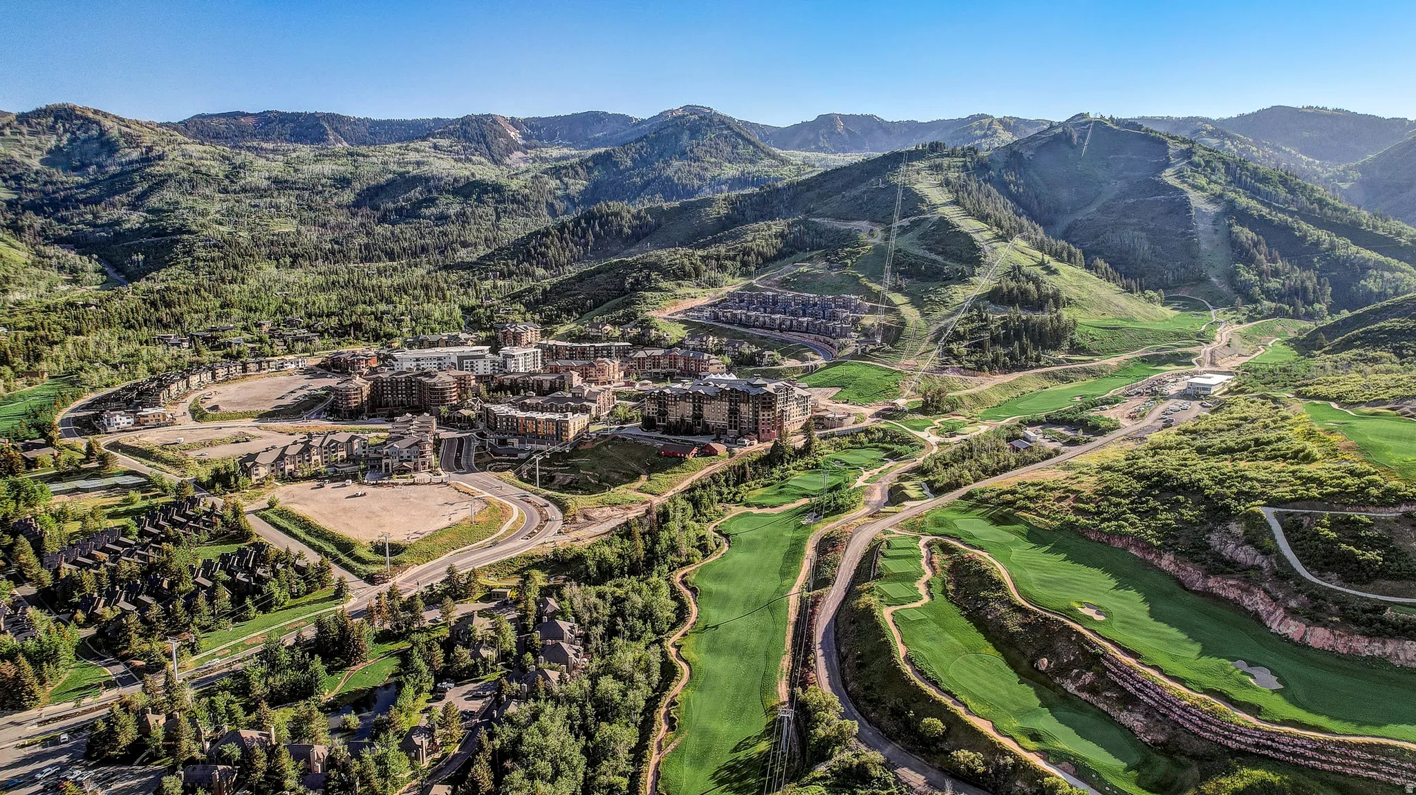 Aerial view of property's location featuring a mountain backdrop and a local golf course