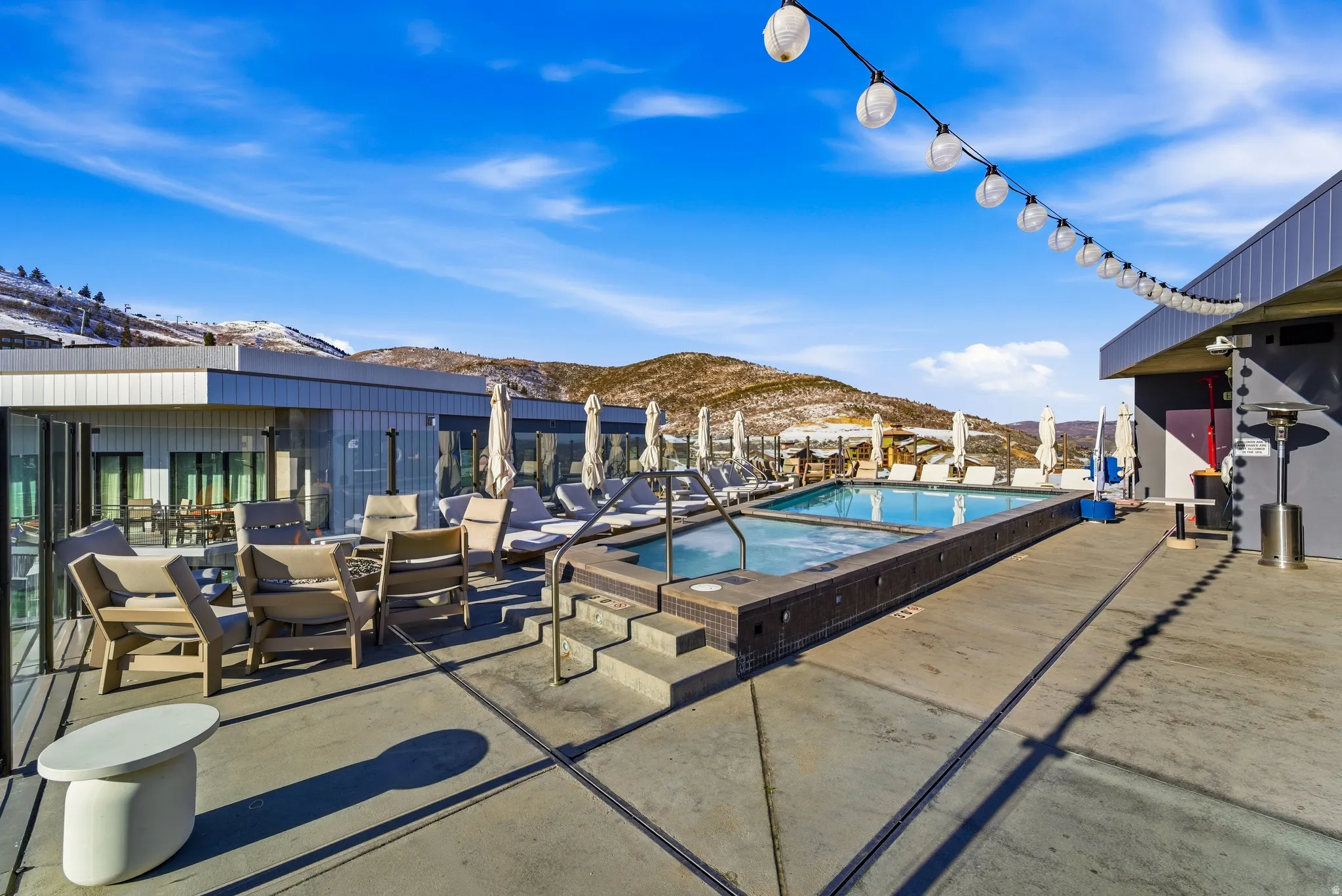 Community pool with a mountain view, a patio, and a hot tub