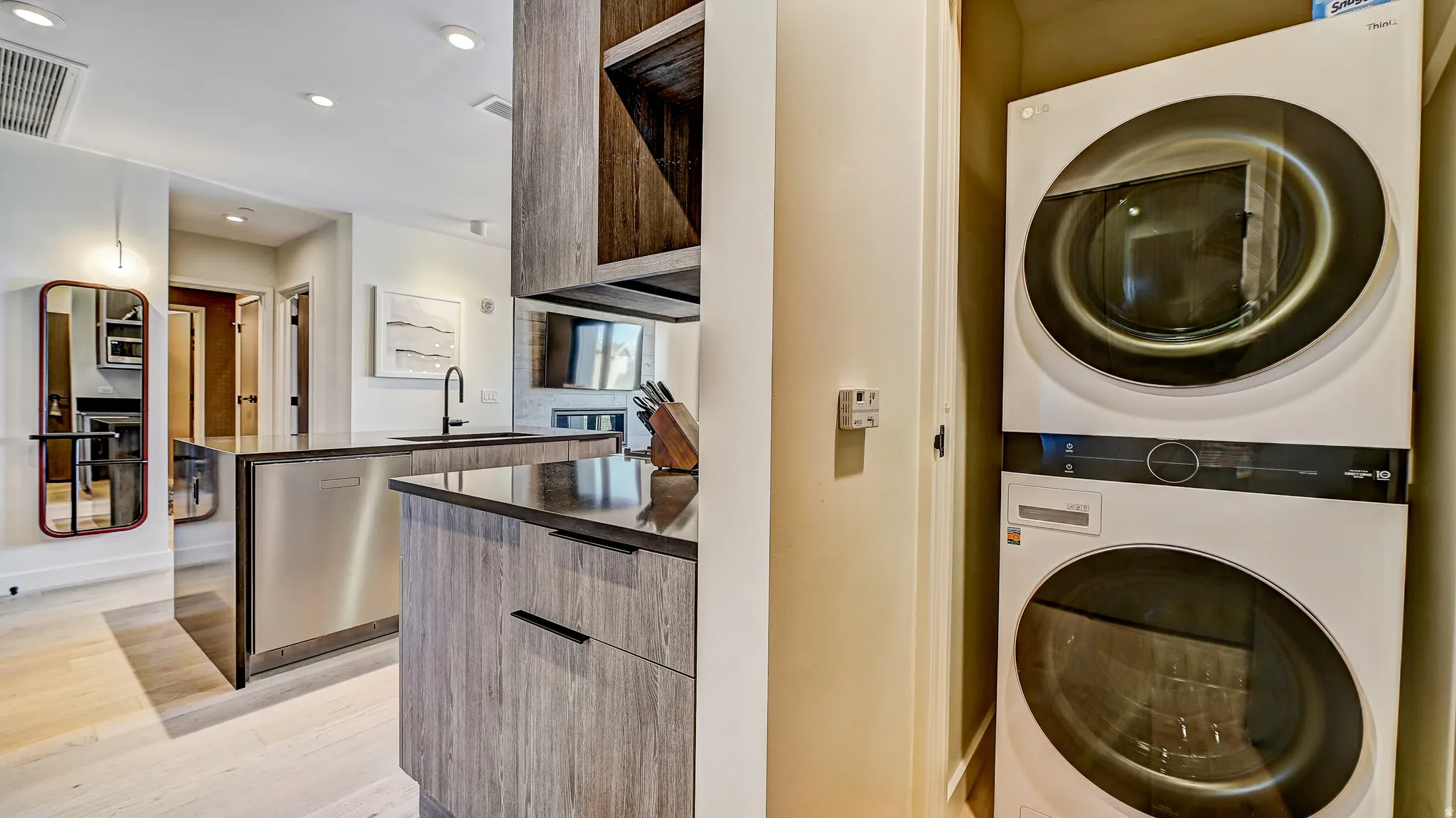 Laundry area featuring stacked washer and dryer, light wood finished floors, and recessed lighting