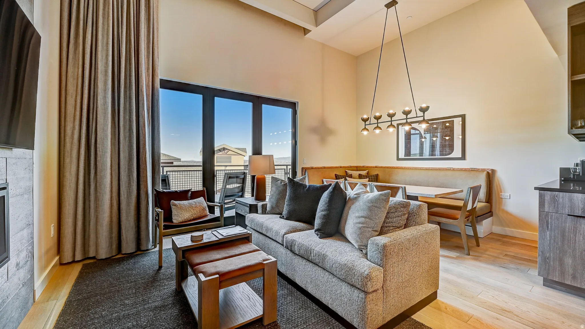 Living area featuring a high ceiling, light wood-type flooring, and a glass covered fireplace
