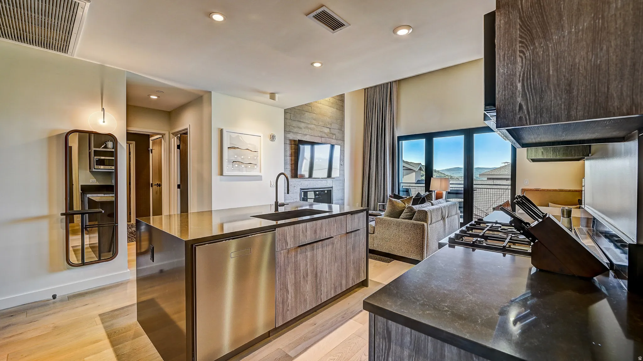 Kitchen with modern cabinets, stainless steel dishwasher, a center island with sink, light wood-type flooring, and open floor plan