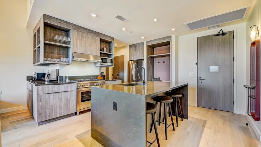 Kitchen with modern cabinets, open shelves, dark stone countertops, premium appliances, and light wood-style flooring