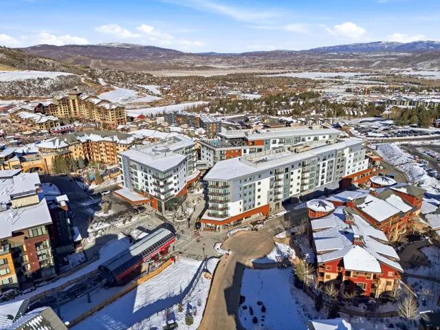 Snowy aerial view featuring a mountain view and a view of apartment building / complex