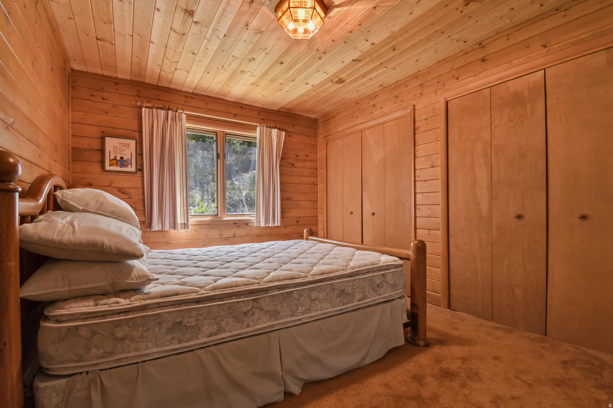 Carpeted bedroom with multiple closets, wood ceiling, and wood walls