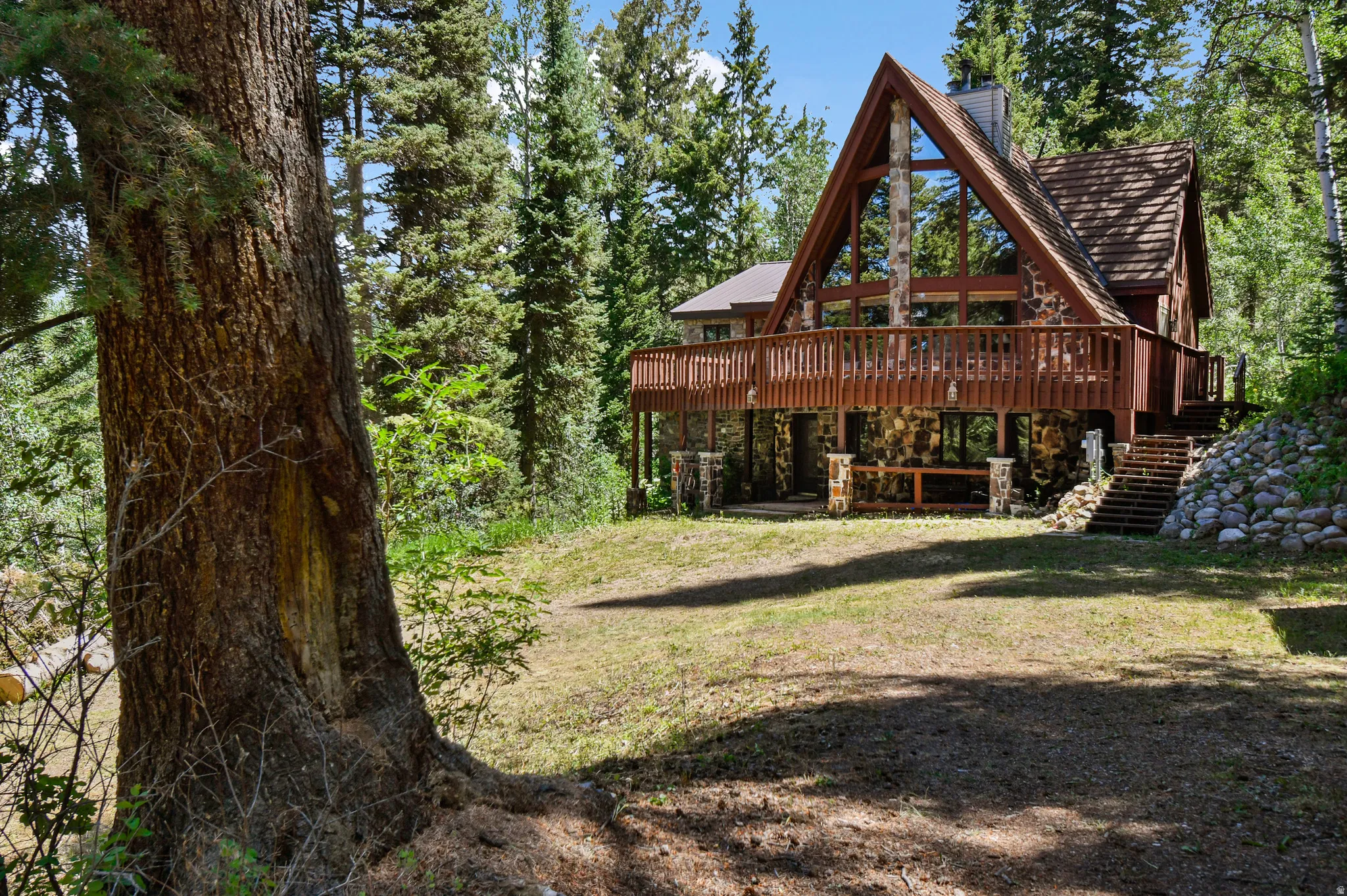 Back of property featuring stone siding, a wooden deck, and a chimney