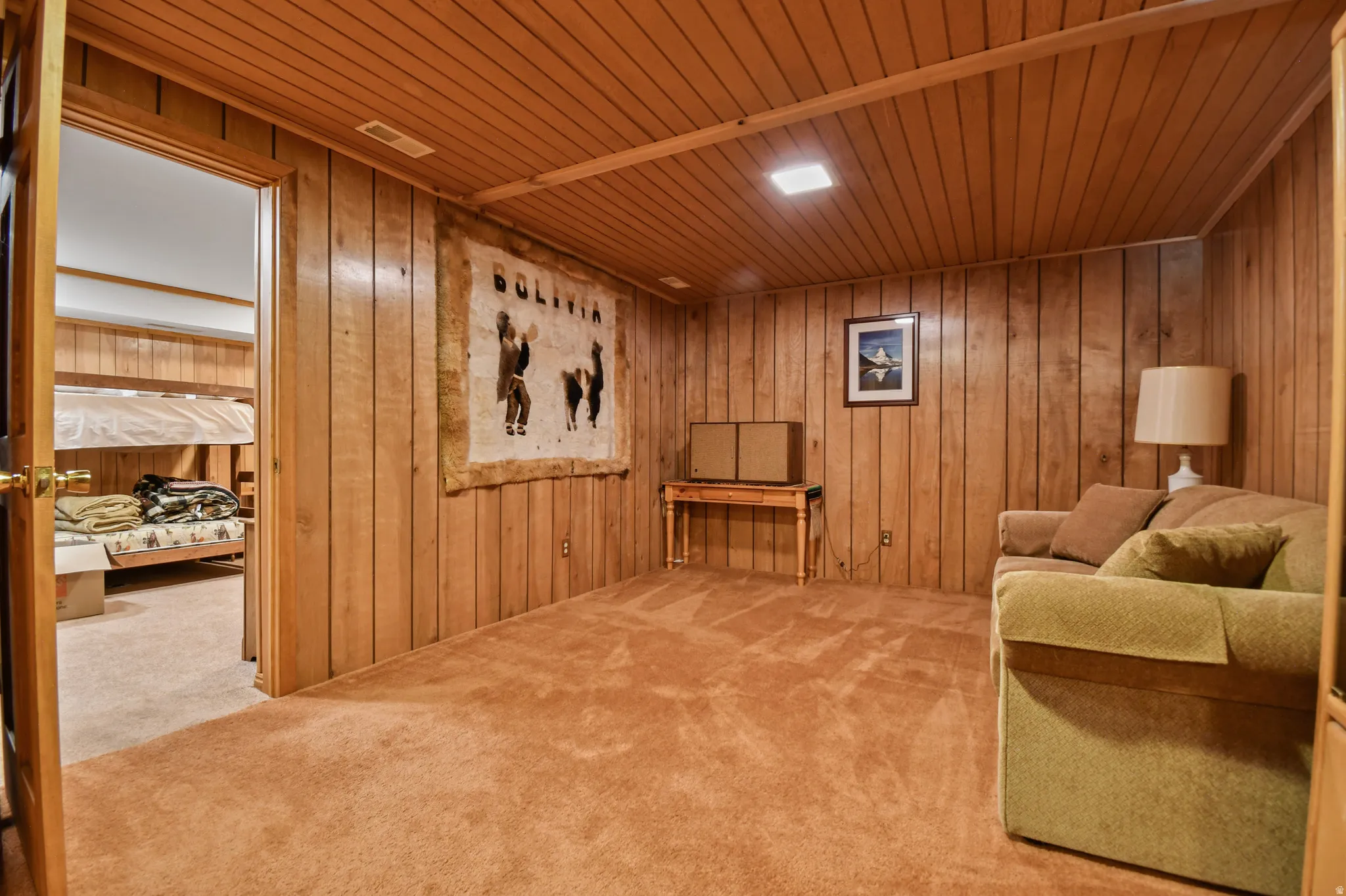 Sitting room with wooden walls, wooden ceiling, and carpet flooring