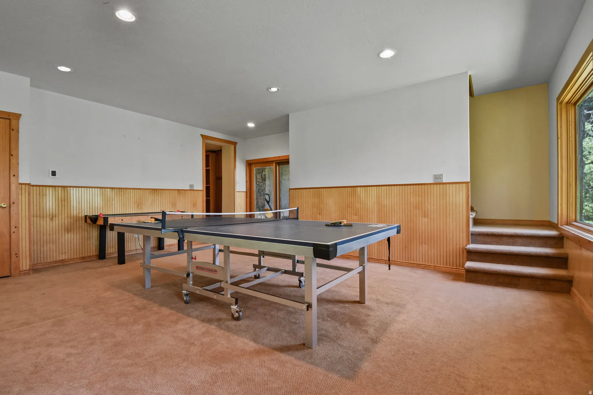 Game room featuring a wainscoted wall, light carpet, wood walls, and recessed lighting