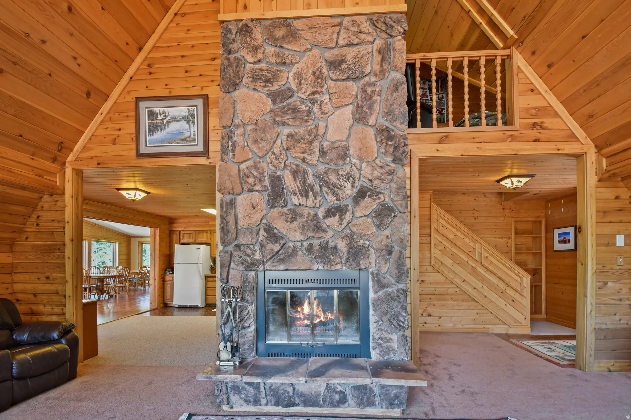 Unfurnished living room with a vaulted wooden ceiling, wood walls, carpet, and a fireplace