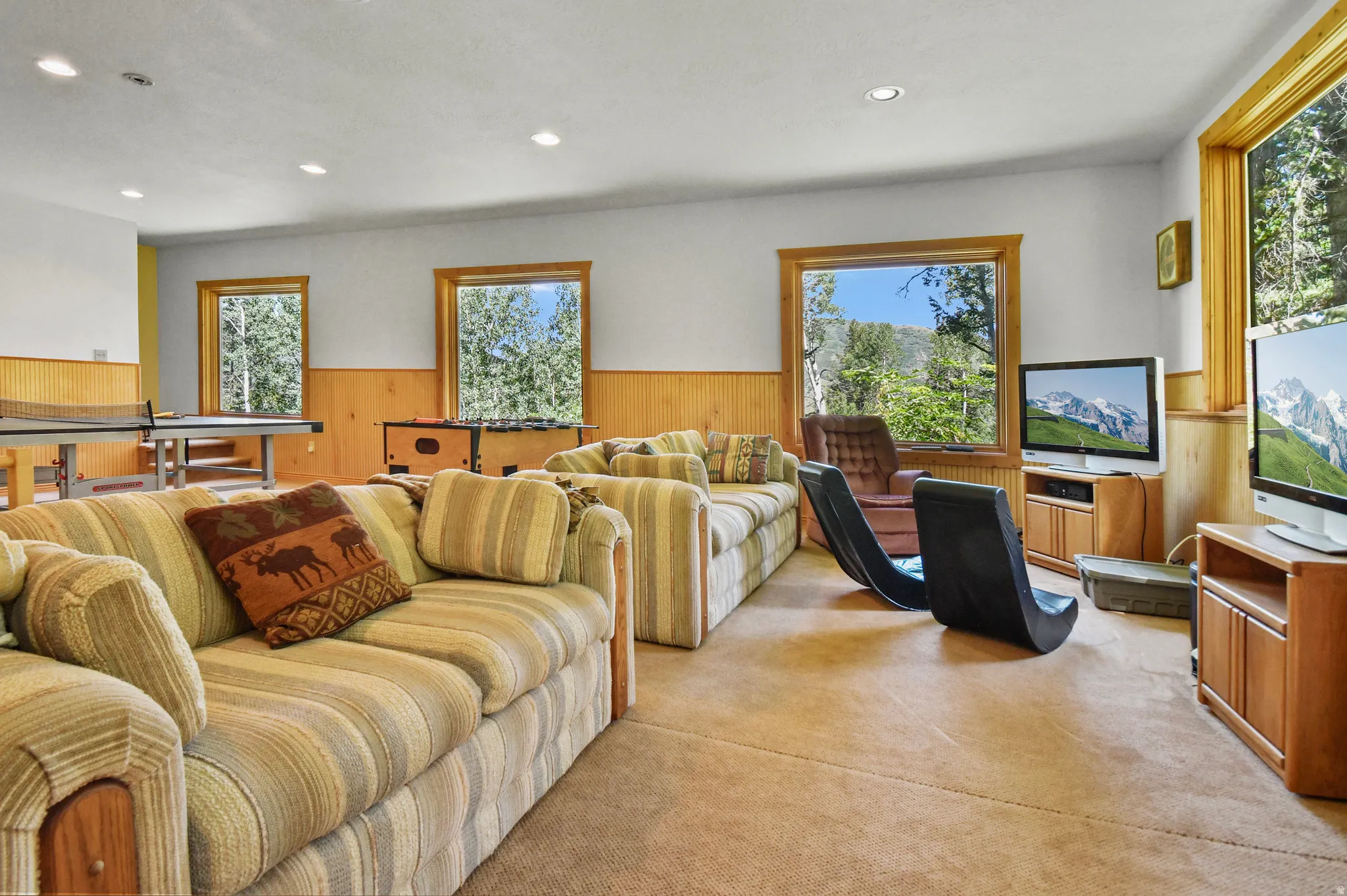 Living area featuring a wainscoted wall, wooden walls, light colored carpet, and recessed lighting