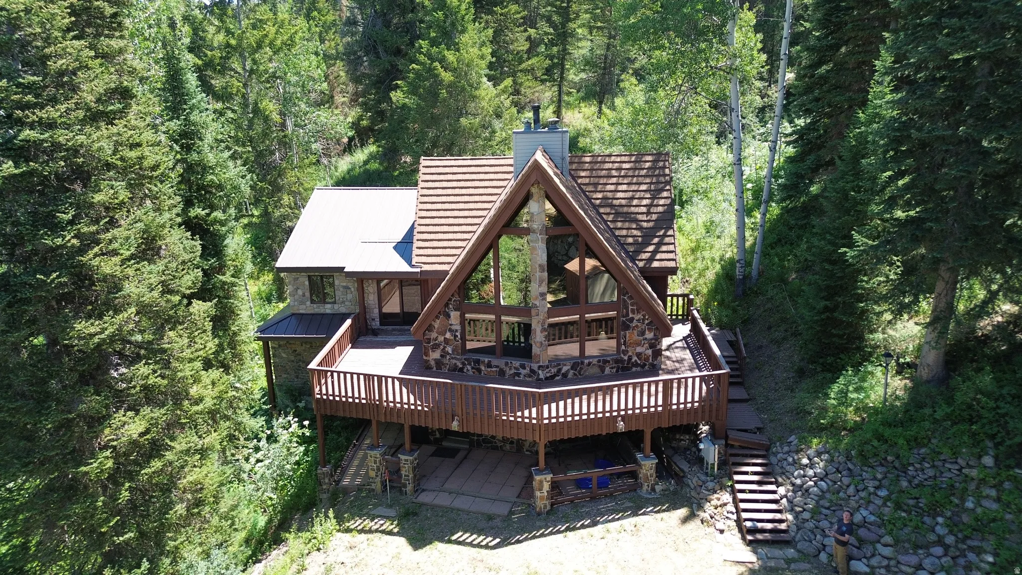 Rear view of property with a wooden deck, a chimney, a metal roof, and a wooded view