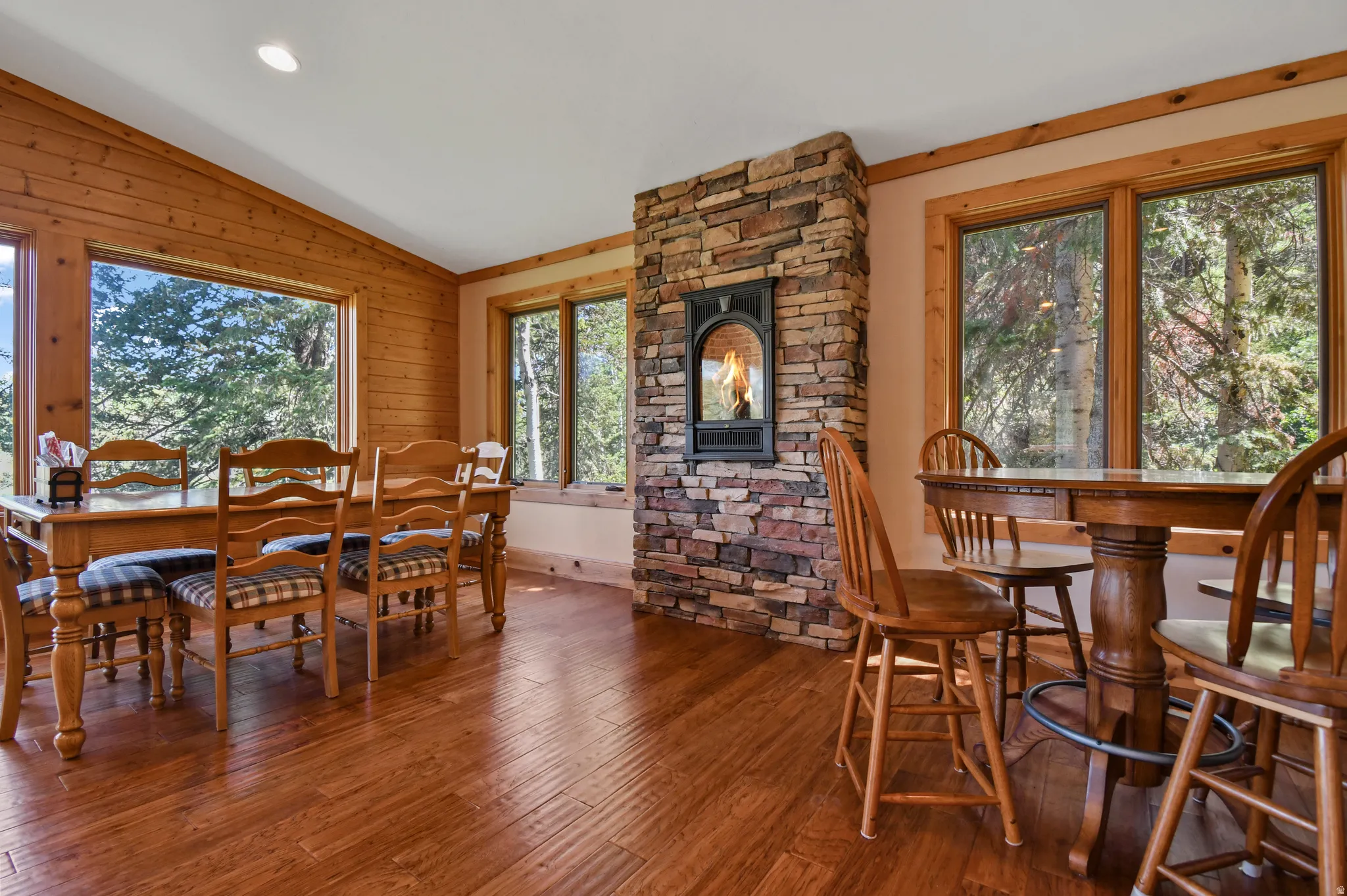 Dining area with hardwood / wood-style floors, vaulted ceiling, wooden walls, and recessed lighting