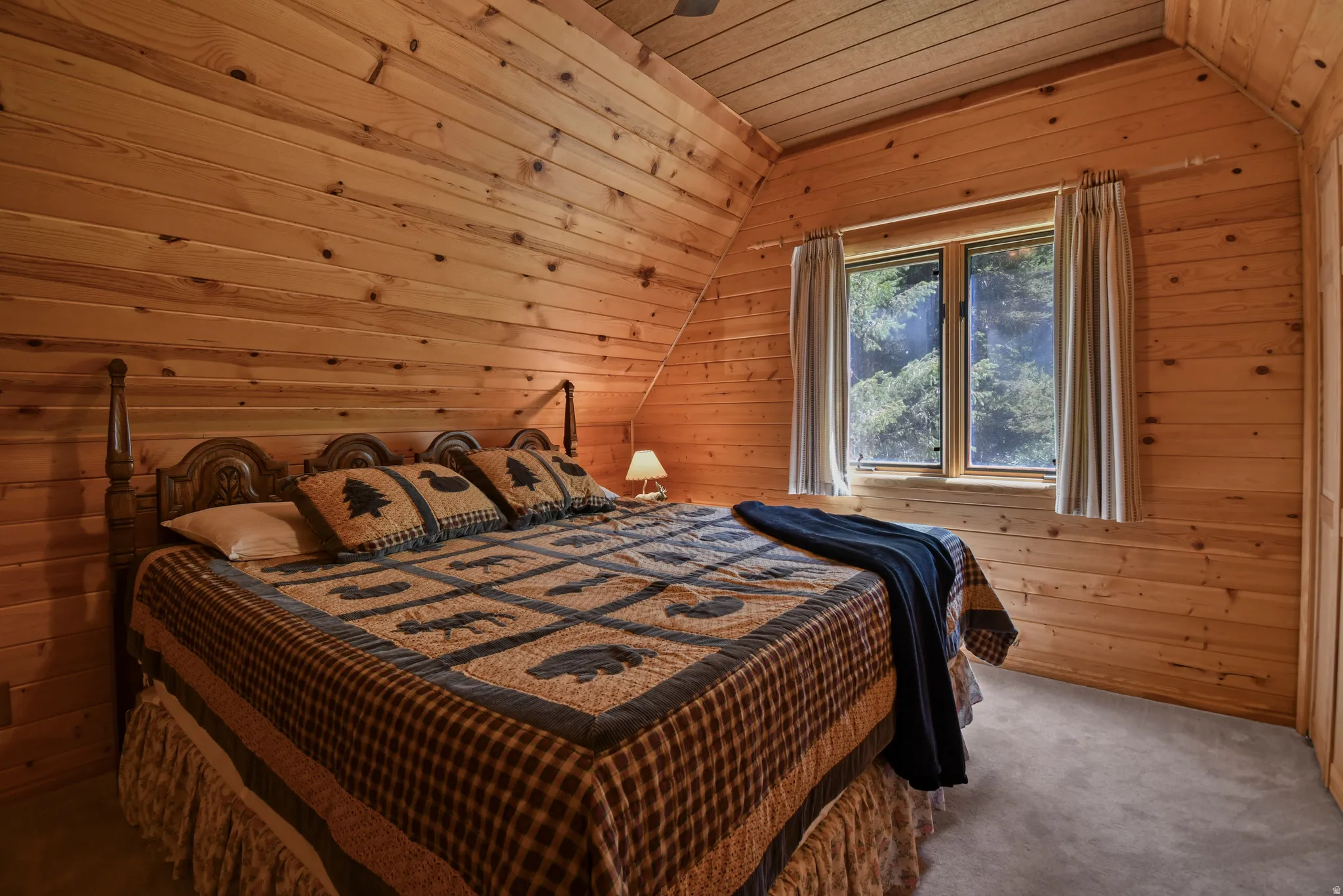 Carpeted bedroom featuring a vaulted wood ceiling and wooden walls