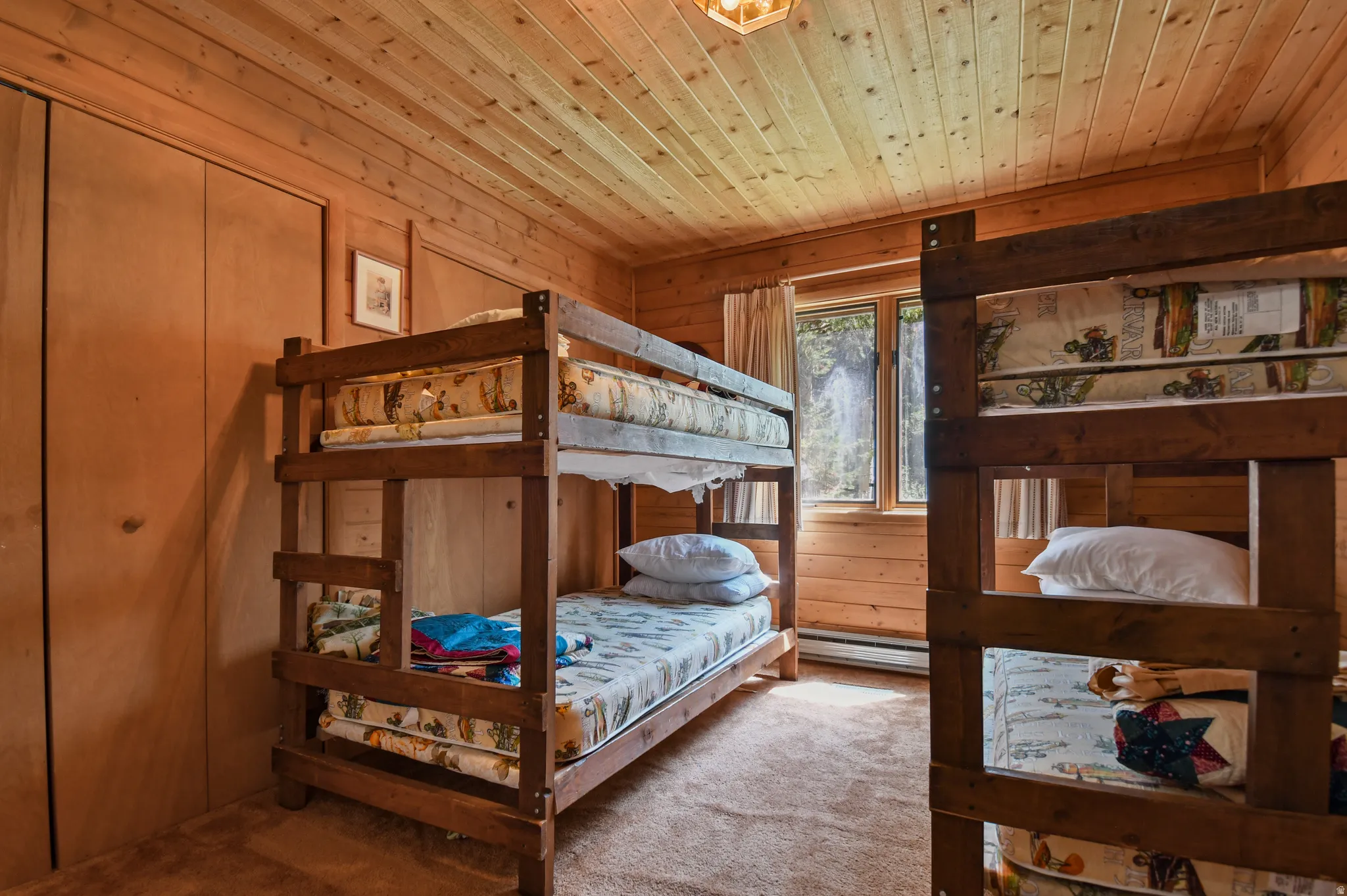 Carpeted bedroom with wood ceiling, wood walls, and baseboard heating