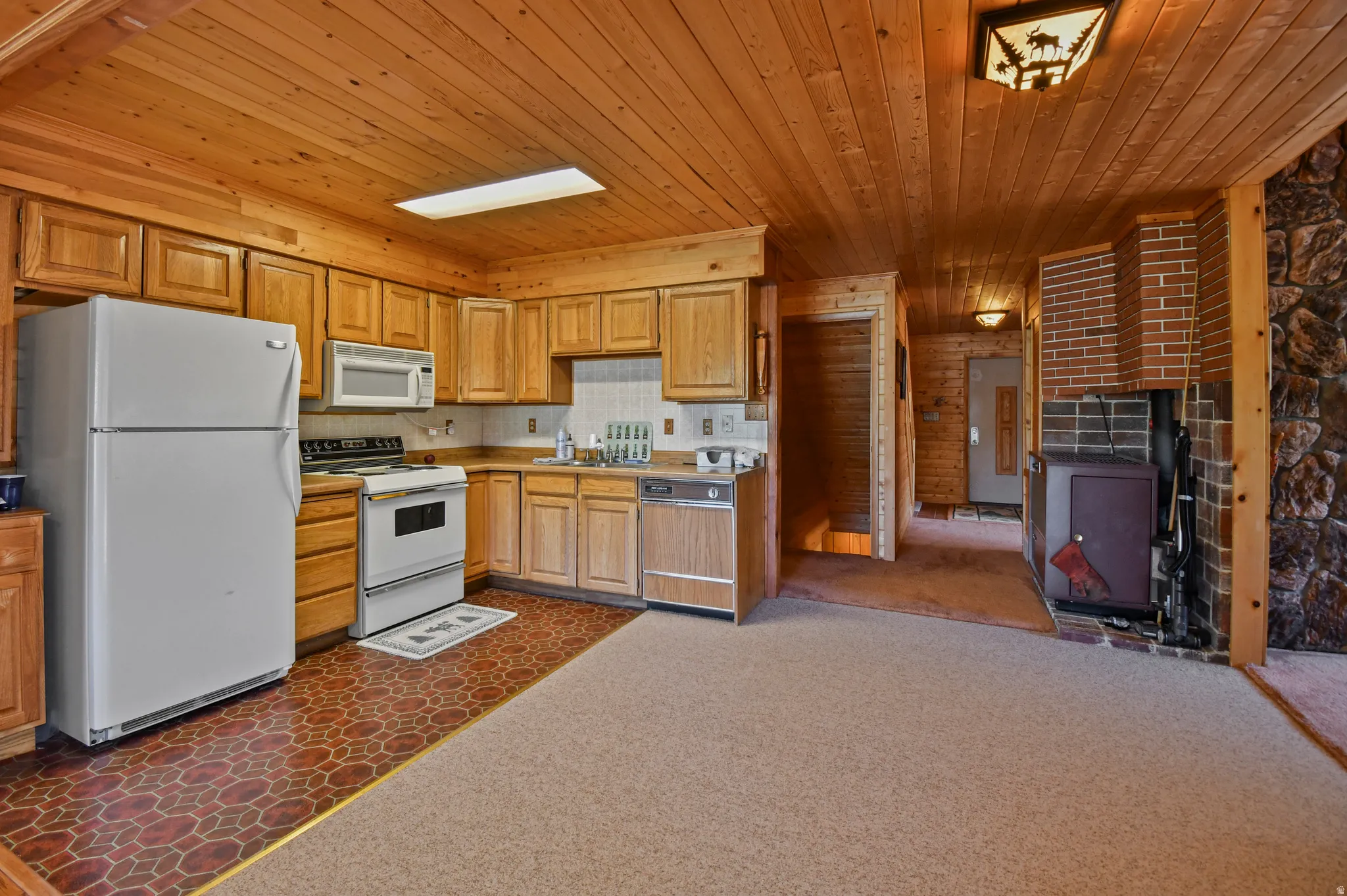 Kitchen featuring white appliances, wood ceiling, dark colored carpet, and light countertops
