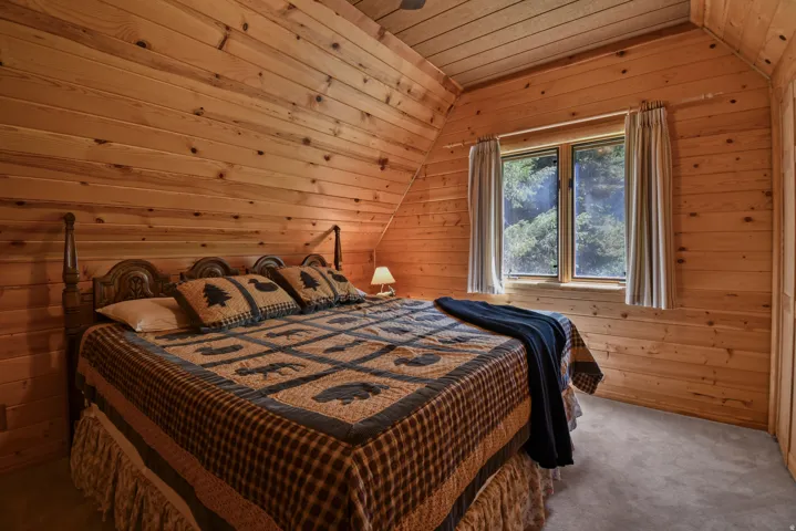 Carpeted bedroom featuring a vaulted wood ceiling and wooden walls